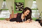 Teenage girl lying on bed with smartphone