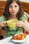 Girl drinking hot chocolate with croissant