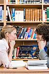 Zwei Studenten sitzen von Angesicht zu Angesicht in einer Bibliothek, Schweden.