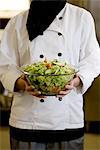 Koch hält eine Schüssel Salat, Schweden.