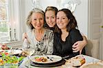 Portrait of a grandmother, daughter and granddaughter at a dinner table, Sweden.