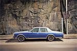 A blue car against a stone wall, Sweden.