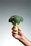 Man holding broccoli in his hand.