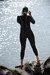 Femme au wetsuit érigé sur un rocher