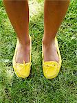 Woman standing on grass with yellow footwear, elevated view