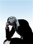 A conceptual image of a  person with his head replaced with the earth, in a position denoting thinking a deep thought.
