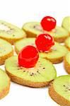 Kiwis slices with cherries closeup over a white background. Small DOF