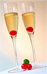 Two champagne cocktails with cherries and warm-coloured background