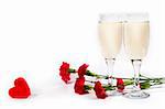 two glasses of champagne, carnation and red plastic heart on white background with copyspace