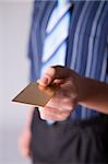 Man's hand holding gold credit card. Focus on the card. Body unfocus.