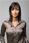 Young woman with telephone headset, isolated on grey background in studio