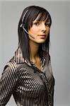 Young woman with telephone headset, isolated on grey background in studio