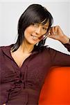 Young attractive woman talking mobile phone. Sitting on the orange sofa.