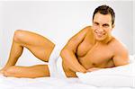 Smiled and happy man lying on the bed. White background in studio.