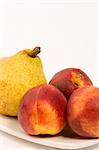 Necterines and a pear set against a plain background