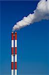 The chimney of a factory with white smoke. Vertical