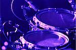 Rock concert series: drum set with microphones, lit by purple and blue