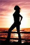 Silhouette of a woman at sunset on the beach.