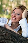 girl laying on a tree and smiling.