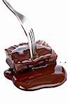 The fork pricking a chocolate cake with syrup on white background