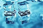 Blue toned ice cubes on reflective surface