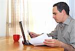 Man sitting at his desk with laptop, papers and credit card