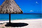 Beautifull white, sandy, tropical beach with a typical straw umbrella for shade, and cristal clear blue, green water.