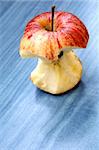 Red apple core standing on blue table