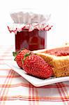 Two strawberries and toasts in a dish, in front of jam jar. Shallow DOF