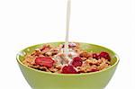 A bowl of cornflakes with fruits and milk being poured. Shallow DOF