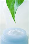 Moisturizing cream and green leaf with water drop on the edge.