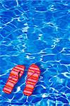 Bright blue pool water background with floating sandals