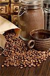 Image of roasted coffee beans, coffee cup, and ground beans on a wooden table.