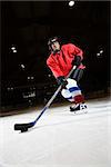 Woman hockey player skating on ice lining up to shoot puck.