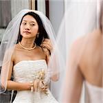 Asian bride looking at herself in a mirror.