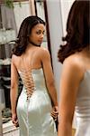 Attractive African-American woman wearing evening gown looking in mirror.