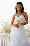 Portrait of African-American bride leaning against railing.