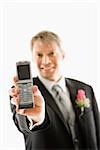 Caucasian groom holding out his cellphone towards viewer.