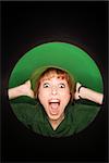 Vignette of Caucasian mid-adult woman with surprised expression wearing hat on green background.