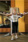 Mature Caucasian adult female using exercise equipment at gym.