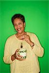 African American female mature adult dipping tea bag in mug.