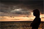 Caucasian teen male standing silhouetted on the shore of Maui, Hawaii, USA