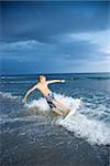 Caucasian male teen riding skimboard.