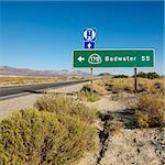 Road sign on side of desert road with direction to Badwater, Death Valley.