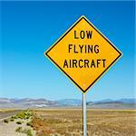 Low flying aircraft sign alongside desloate highway.