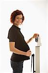 Pregnant Caucasian mid-adult woman standing on scale with head turned toward viewer smiling.