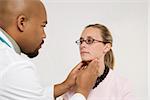 Mid-adult African-American doctor examining Caucasion mid-adult female patient.