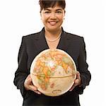 Filipino middle-aged businesswoman holding globe in both hands standing in front of white background.