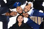 Low angle portrait  of multi-ethnic business group of men and women in huddle looking at viewer.