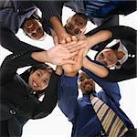 Low angle portrait  of multi-ethnic business group of men and women with hands in huddle.